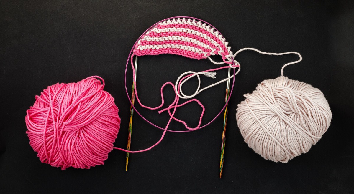 Two wooden circular knitting needles with balls of yarn